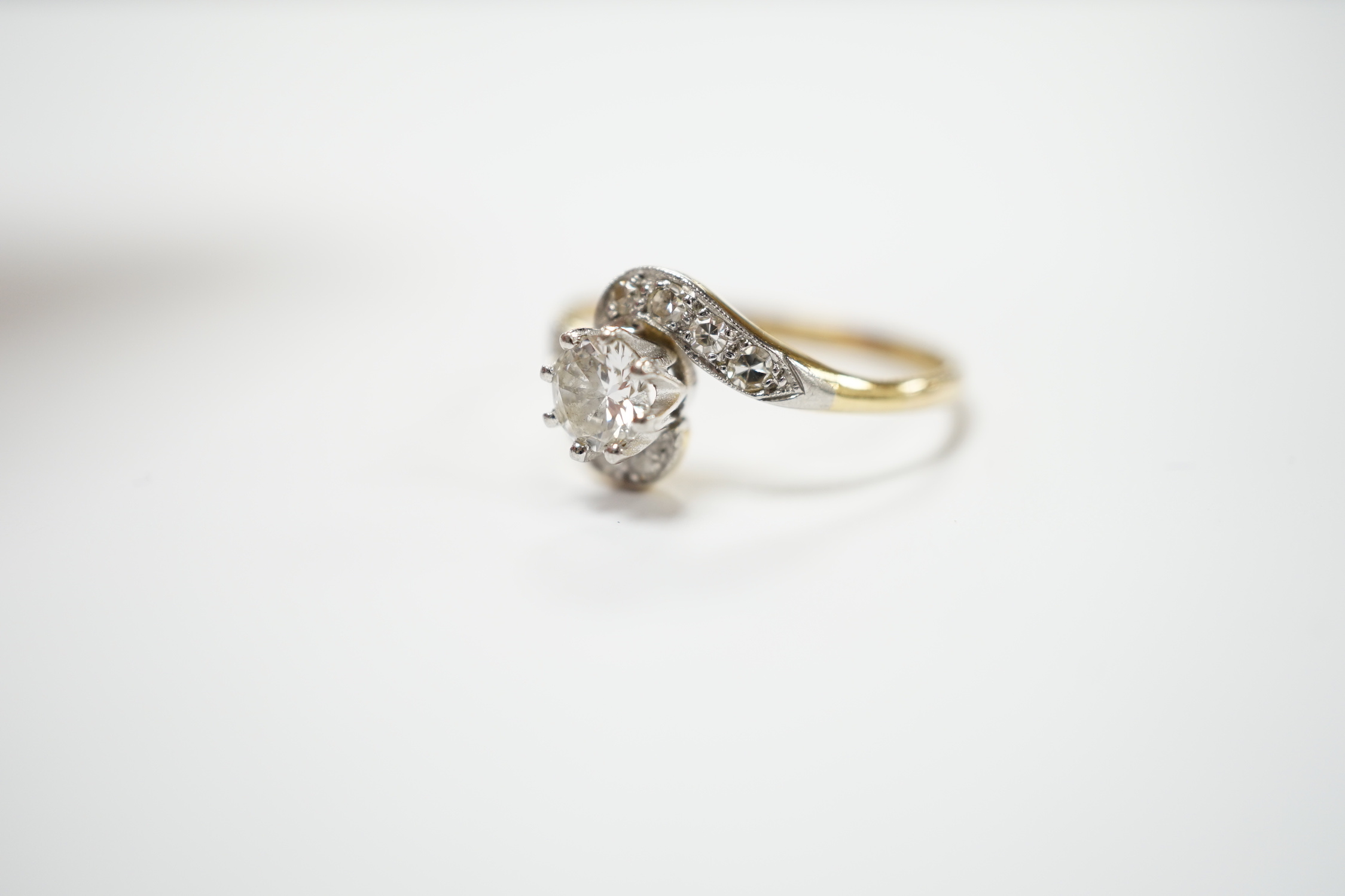 An 18ct, plat and single stone diamond set ring, with diamond chip set crossover shoulders, size P/Q, gross weight 3.1 grams.